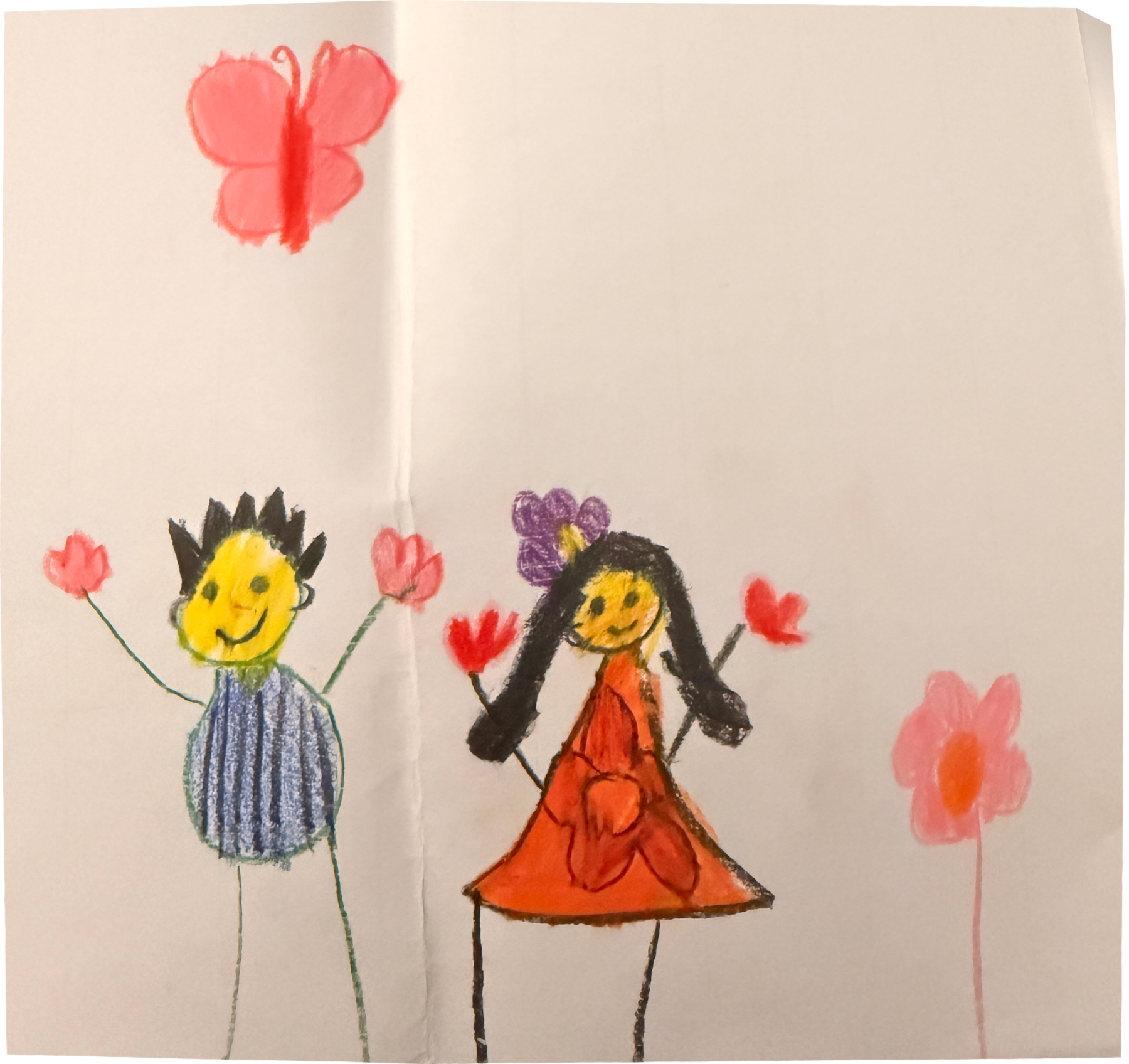 A crayon drawing by Marcus's sister when she was little: a smiling figure with spiky black hair and a striped blue top and a figure in an orange dress with a purple flower in her hair, both holding up red flowers, with a pink butterfly above and a tall pink flower beside them. The paper is folded down the middle and creased across one corner.