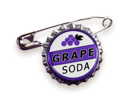 A Grape Soda bottle cap badge from Up, purple and white with a cluster of grapes and a bird, fixed to the board with its own safety pin